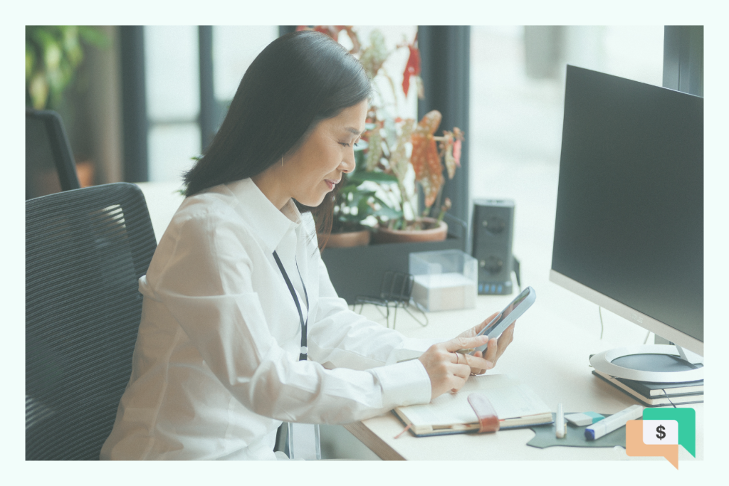 woman sitting at a desk and looking at her mobile phone